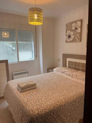 a bedroom with a bed and a chandelier at Apartamento junto al paseo marítimo de Cee in Cee