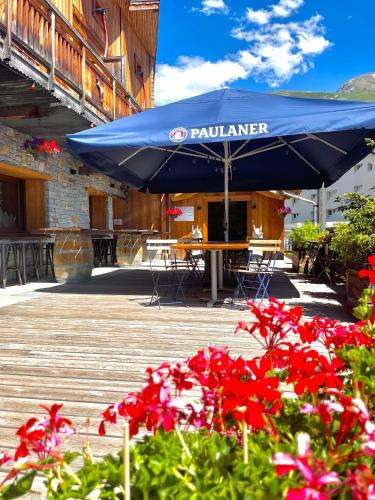 a blue umbrella on a table with red flowers at Chamois Lodge in Les Deux Alpes