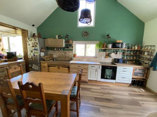 une grande cuisine avec une table et des chaises en bois dans l'établissement Chambre cosy en pleine nature, proche de Dijon, à Val-Suzon