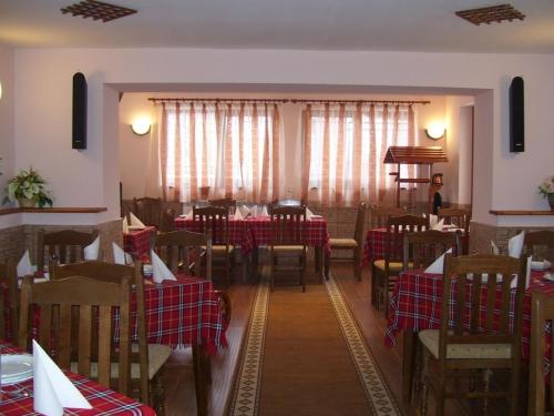 uma sala de jantar com mesas e cadeiras com toalhas de mesa vermelhas e brancas em Kashta Peychevi em Govedartsi
