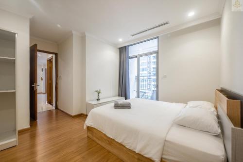 a bedroom with a white bed and a large window at Landmark Plus Vinhomes CityView Suite in Ho Chi Minh City