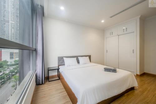 a bedroom with a white bed and a large window at Landmark Plus Vinhomes CityView Suite in Ho Chi Minh City