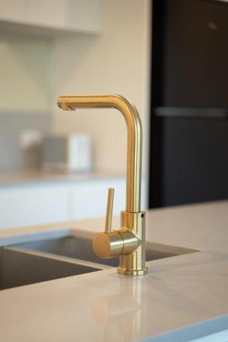 a kitchen sink with a gold faucet on a counter at Prime CBD 3BR 2 free parking apartment next to canberra centre in Canberra
