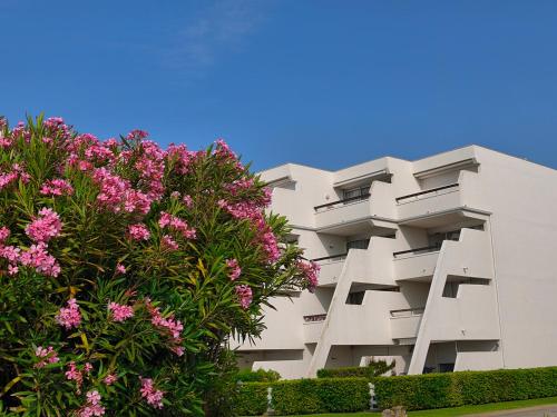 ein weißes Gebäude mit rosa Blumen davor in der Unterkunft Adoya plage Studio cabine vue port et mer in Le Grau-du-Roi
