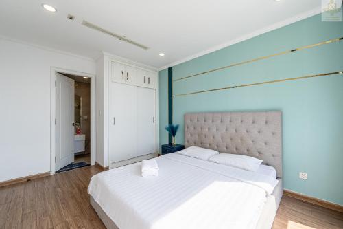 a bedroom with a white bed with a blue wall at Landmark Plus Vinhomes CityView Suite in Ho Chi Minh City
