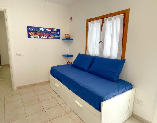 a bedroom with a bed with blue sheets and a window at MARECHIARA Apartment - Independent ground-floor unit in central Nettuno with private patio, just 50 m from the sea and steps from the train station in Nettuno