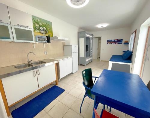 a kitchen with a table and a blue table and chairs at MARECHIARA Apartment - Independent ground-floor unit in central Nettuno with private patio, just 50 m from the sea and steps from the train station in Nettuno