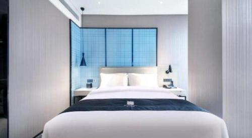 a bedroom with a large white bed with a window at Echarm Hotel Xiangyang Erqi in Xiangyang