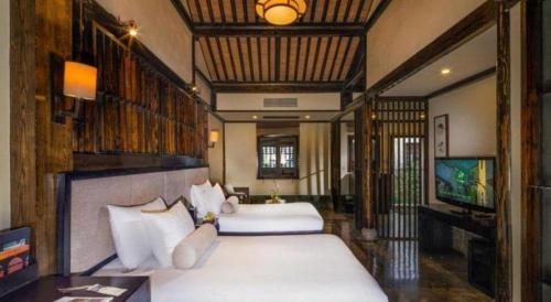 a bedroom with two beds and a television in it at Hotel Dayu Kaiyuan in Shaoxing