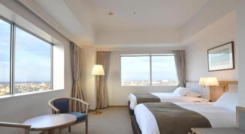 a hotel room with two beds and large windows at Grand Hotel New Oji in Tomakomai