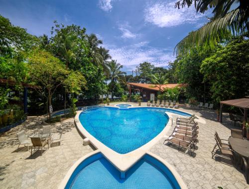 a pool at a resort with chairs and a table at Aninga Lodge in Tortuguero