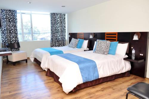 a bedroom with two beds and a desk at Hotel de las Américas - Ambato in Ambato