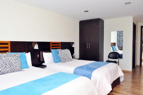 Hotel de las Américas - Ambato في أمباتو: غرفة فندقية بسريرين ومكتب