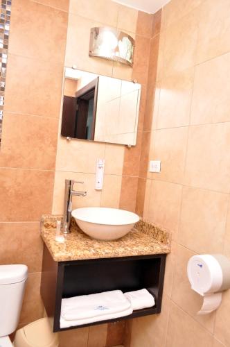 a bathroom with a sink and a toilet and a mirror at Hotel de las Américas - Ambato in Ambato