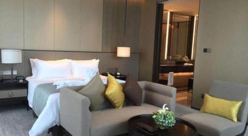 a hotel room with a bed and a couch and a table at Golden Eagle Summit Hotel Kunshan in Suzhou