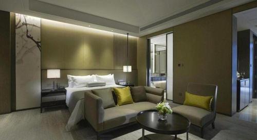 a hotel room with a bed and a couch and a table at Golden Eagle Summit Hotel Kunshan in Suzhou