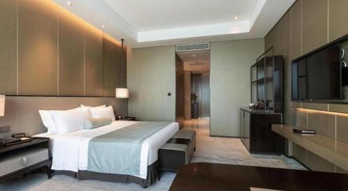 a hotel room with a bed and a television at Golden Eagle Summit Hotel Kunshan in Suzhou