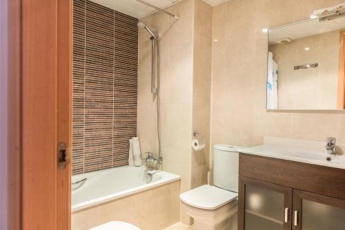 y baño con aseo, bañera y lavamanos. en Apartamentos Navas 2, en Barcelona
