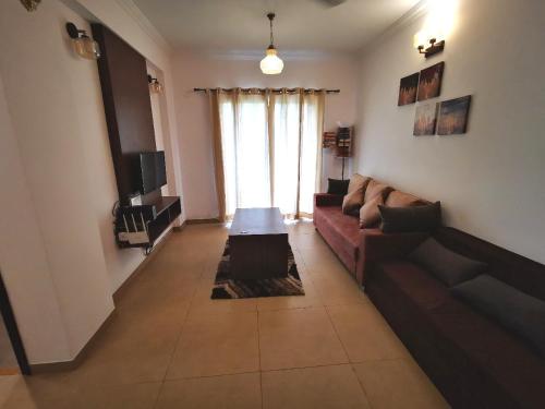 a living room with a couch and a tv at Ronnie's Studio Apartment in Arpora
