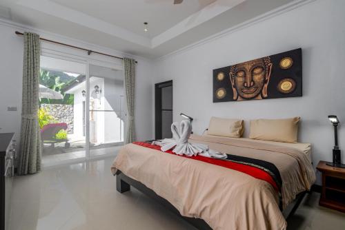 a bedroom with a bed with a painting on the wall at Luxurious & Quiet Pool Villa Orchid in Nai Yang Beach
