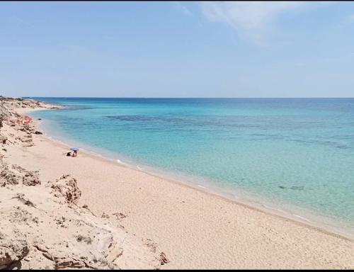 a beach with blue water and a person on it at B&B Sole Mare Vento in Maruggio