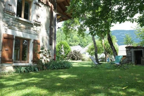 deux chaises assises sur la pelouse à côté d'une maison dans l'établissement La Bergerie apartment in an old farmhouse!, à Nâves-Parmelan