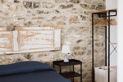 a bedroom with a stone wall with a bed and a lamp at Casolare Cento Ulivi Luxury & Charme in Ascea