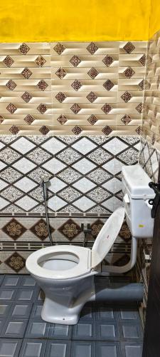 a bathroom with a toilet and a tiled wall at White Sands Cottage in Alleppey