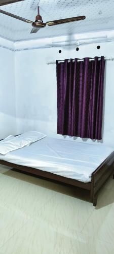 a bed in a room with a purple curtain at White Sands Cottage in Alleppey