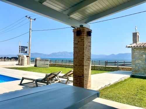 a patio with a table and chairs and the ocean at Costa Kalamos Suites in Kalamos