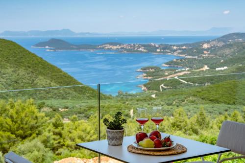 a table with two glasses of wine and a plate of fruit at Ninemia Luxury Residence in Perdika