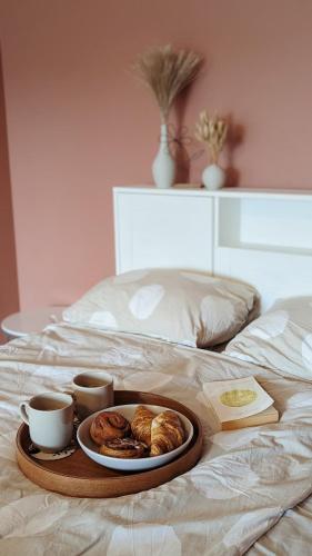 a tray of pastries and cups of coffee on a bed at Ezerkrasta apartamenti in Liepāja