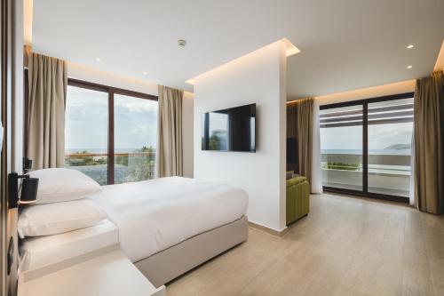 a white bedroom with a large bed and a television at Radisson Resort Ruza Vjetrova in Dobra Voda