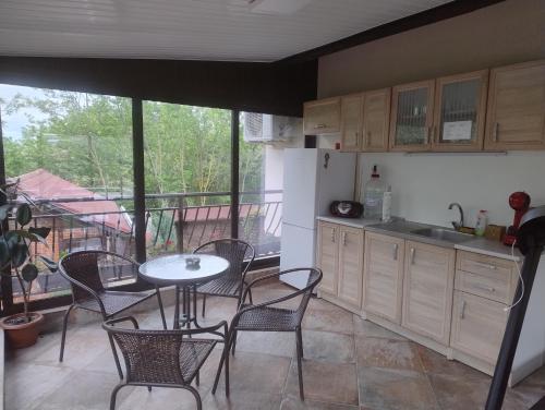 a kitchen with a table and chairs and a balcony at Къща за гости АКАЦИЯ in Ravna Gora