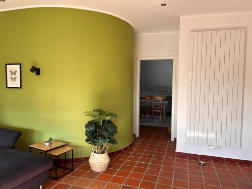 a living room with a green wall and a plant at Vechte-Palais obere Wohnung in Metelen