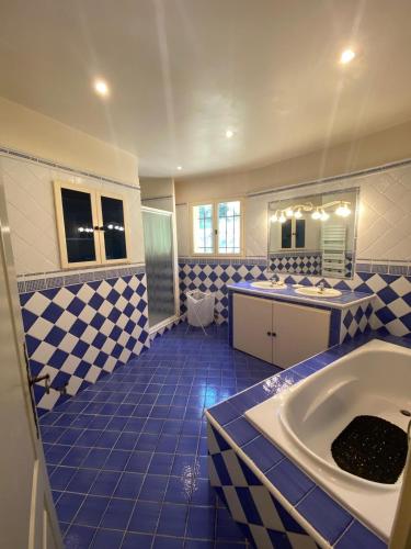 La salle de bains bleue et blanche est pourvue d'une baignoire et d'un lavabo. dans l'établissement Tranquillité et authenticité dans les hauteurs, à Le Tignet