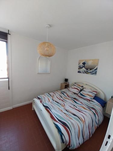une chambre avec un lit dans une pièce blanche dans l'établissement Appartement T2 lumineux à 200m de la plage, tout équipé, à Port-la-Nouvelle