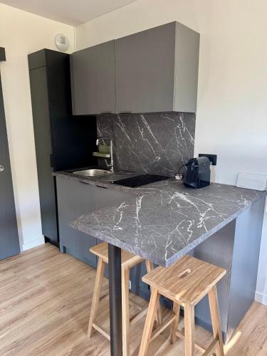 une cuisine avec un comptoir en marbre et des tabourets en bois dans l'établissement Lodge sous les oliviers, à Propriano