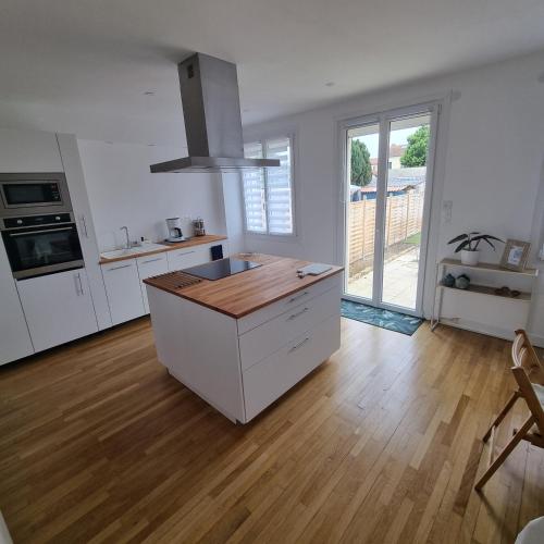 una cucina con mobili bianchi e pavimento in legno di Maison cosy avec Balnéo & jardin a Chalons en Champagne