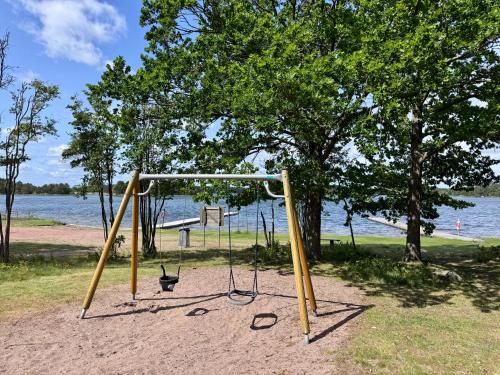 a swing set in a park next to the water at Vacation villa with fenced yard in Blomstermåla
