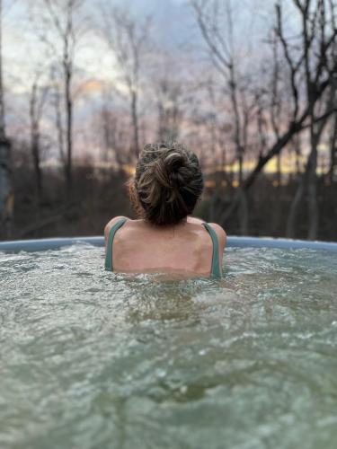 a person in the water in a hot tub at River Camp in Lembuži