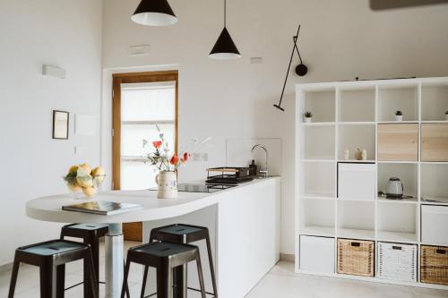 a kitchen with white cabinets and a white island with stools at Casolare Cento Ulivi Luxury & Charme - Villa exclusive use in Ascea