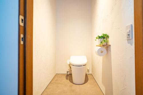 a bathroom with a toilet with a plant on the wall at J&B namuya Villa in Minamiboso