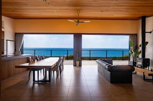 a dining room with a table and a view of the ocean at J&B namuya Villa in Minamiboso