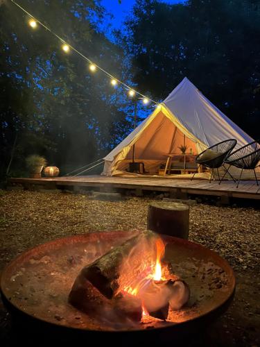 a tent with a campfire and a fire pit with a tent at River Camp in Lembuži