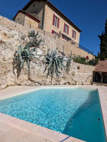 une piscine bleue en face d'un mur en pierre dans l'établissement Maison de campagne 4 couchages avec piscine et lacs, à Sainte-Radegonde