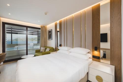 a bedroom with a large white bed and a chair at Radisson Resort Ruza Vjetrova in Dobra Voda