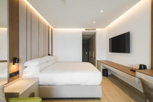 a bedroom with a white bed and a television at Radisson Resort Ruza Vjetrova in Dobra Voda