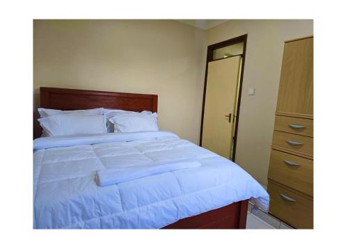a bedroom with a large white bed and a dresser at A private bedroom in a shared home in Arusha in Arusha