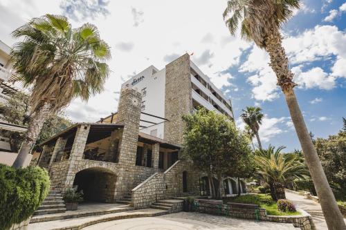 a building with palm trees in front of it at Radisson Resort Ruza Vjetrova in Dobra Voda